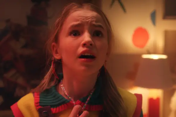 Nell Fisher as Holly Wheeler in Stranger Things looking scared as she stands in her bedroom.