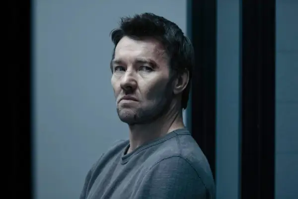Joel Edgerton in Dark Matter, wearing a grey shirt and sat in a grey room