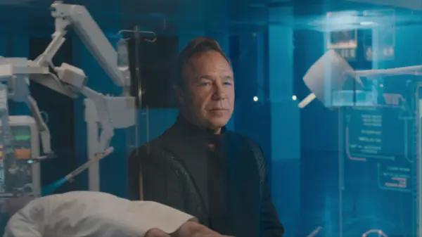 Stephen Graham as Elias Mannix in Bodies sitting watching an operation through a window