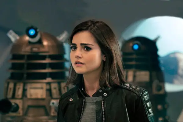 Clara Oswald stood in front of two Daleks in Doctor Who.