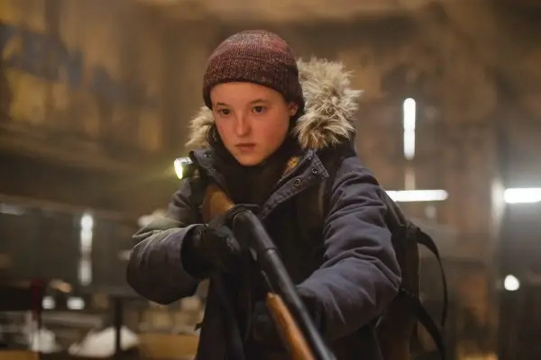 Ellie (Bella Ramsey) in The Last of Us season 2, wearing a thick coat and holding a shotgun.