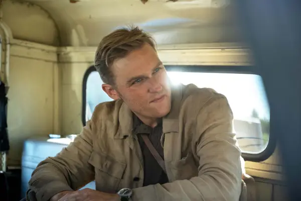 Wyatt Russell stars in Monarch: Legacy of Monsters wearing a brown jacket, sat in the back of a van
