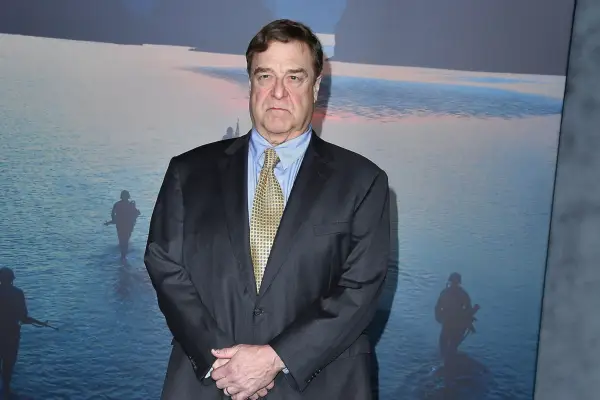 John Goodman wearing a suit with his hands by his waist