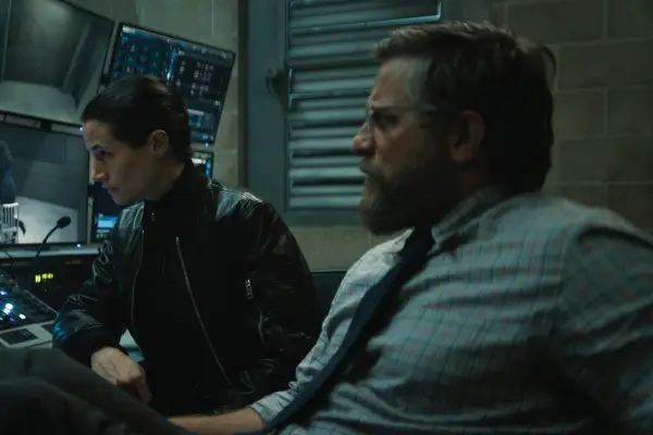 Elisa Lasowski as Duvall and Joe Tippett as Tim in Monarch: Legacy of Monsters leaning over a control board.