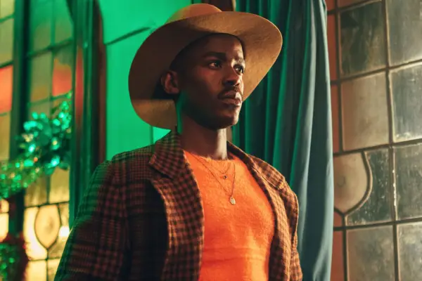 The Doctor sports a cowboy hat, bright orange T-shirt and jacket