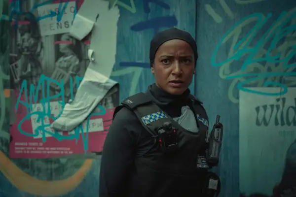 Amaka Okafor as DS Hasan in Bodies wearing a police officer uniform standing in an alleyway.