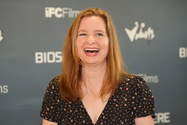 Lennon Parham laughs at a press event, wearing a black patterned V-neck top