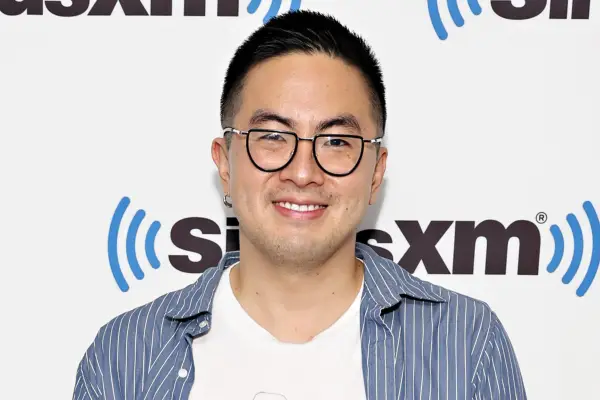 Bowen Yang wears a white t-shirt and blue overshirt at a SiriusXM event