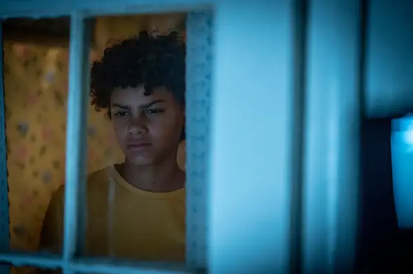 Charlie looks outside a window with a suspicious, concerned look