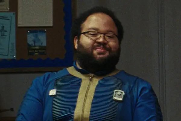 Zach Cherry stars in Fallout in blue and yellow overalls