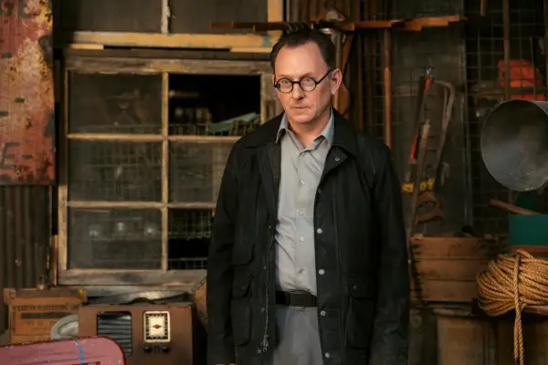 Michael Emerson as Wilzig in Fallout in a long jacket and grey shirt and trousers