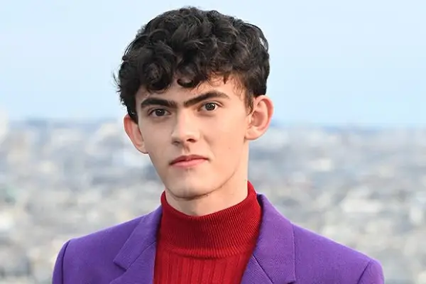 Joe Locke in a red jumper and purple blazer.