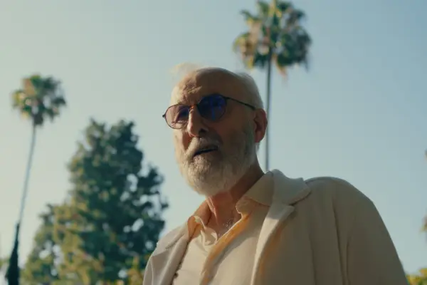 James Cromwell in Sugar, wearing sunglasses and a white suit and walking amongst palm trees