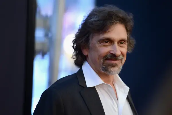 Dennis Boutsikaris smiling and wearing a white shirt and black jacket