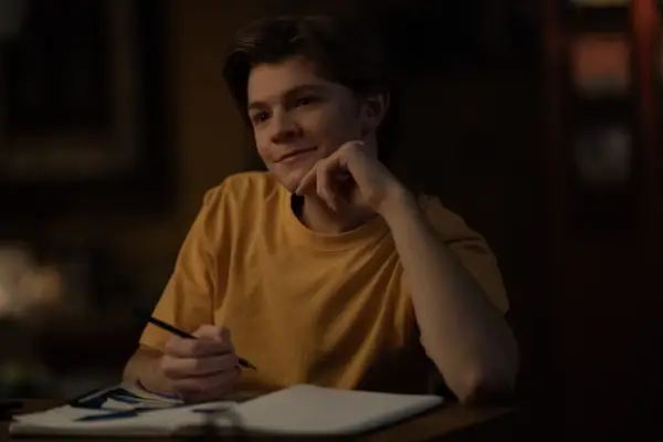 Oakes Fegley in Dark Matter wearing a yellow T shirt and writing on a piece of paper