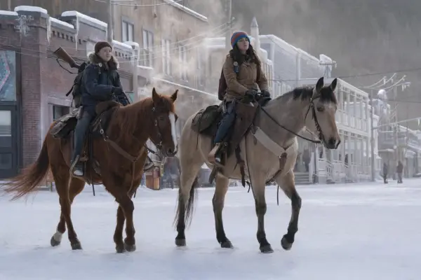Bella Ramsey as Ellie and Isabela Merced as Dina in The Last of Us, riding horses through the snow
