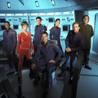 Star Trek: Enterprise cast on set: Anthony Montgomery, Jolene Blalock, Dominic Keating, Scott Bakula, Linda Park, Connor Trinneer and John Billingsley gathered in the cockpit looking into camera