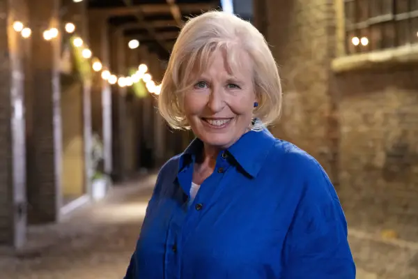 Sylvia Noble (Jacqueline King) in Doctor Who wearing a blue shirt, smiling into camera