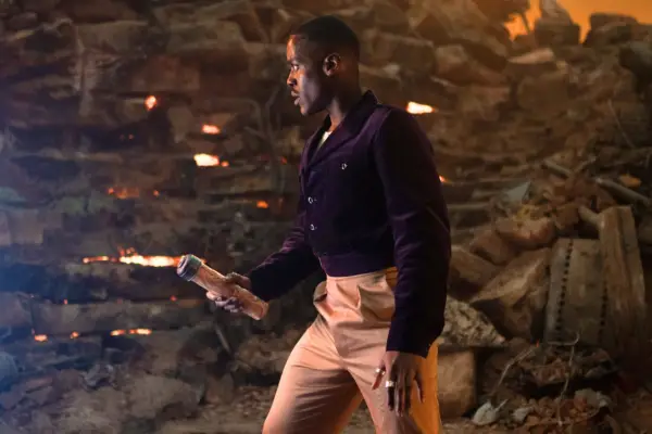 Ncuti Gatwa as The Doctor in Doctor Who holding a flare in a rocky environment