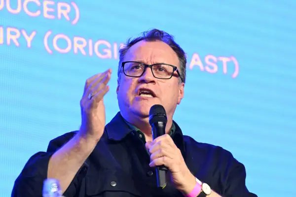 Russell T Davies holds a microphone while speaking on stage