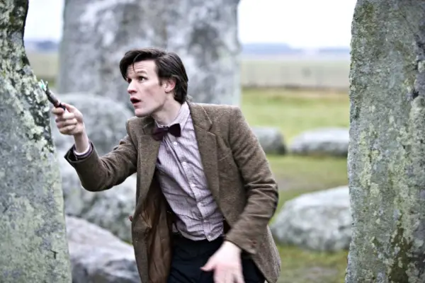 Matt Smith as the Eleventh Doctor holding his sonic screwdriver. He is surrounded by rocks and looks surprised.