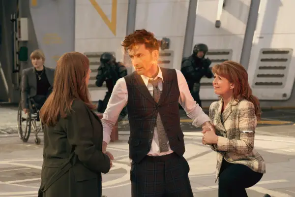 Catherine Tate as Donna Noble, David Tennant as The Doctor and Bonnie Langford as Mel in Doctor Who. All three are leaning down, Mel and Donna are holding the Doctor