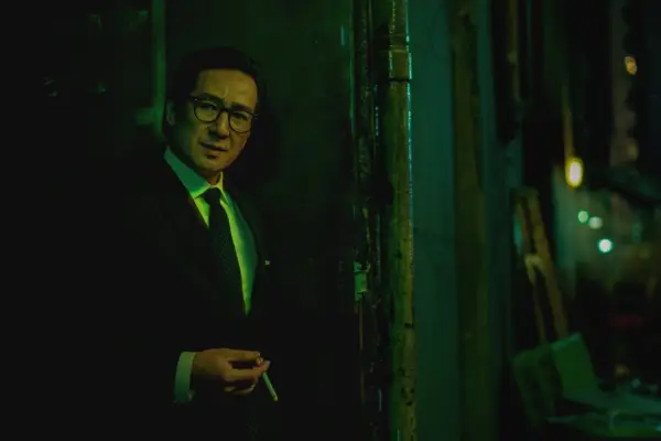 Ke Huy Quan in Everything Everywhere All At Once wearing a suit, holding a cigarette
