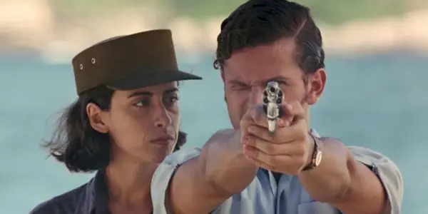 A female soldier looking at a man aiming a gun in 