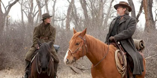 Mattie Ross and Rooster Cogburn talking while riding horses in True Grit.