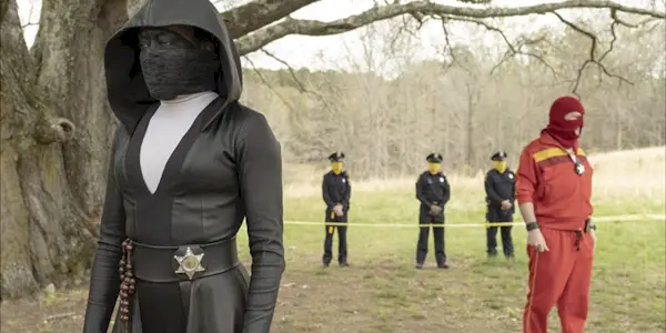 Sister Night standing in an open field with cops behind her in Watchmen