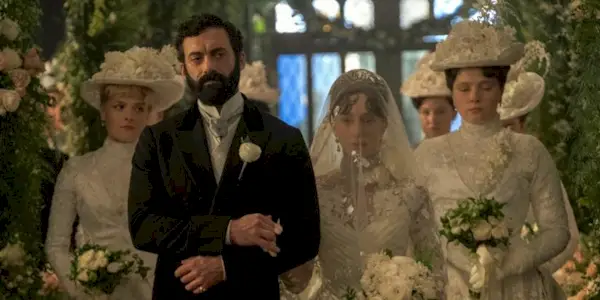Taissa Farmiga as Gladys walking down the aisle in her veil with Morgan Spector as George in The Gilded Age.