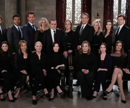 The cast of Season 61 of General Hospital, wearing black and sitting in a dark church.