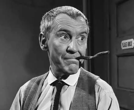 Burgess Meredith standing with a crooked cigar in his mouth in The Twilight Zone