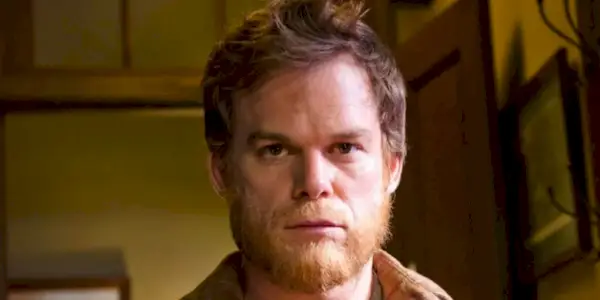 A closeup of Michael C. Hall as Dexter with shaggy hair and a beard looking blankly ahead in Dexter.