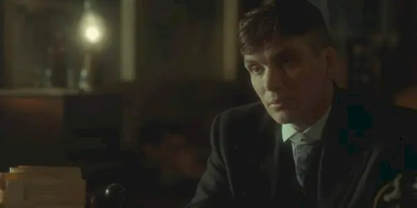 Cillian Murphy, wearing a suit and looking at something, in 