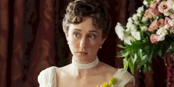 Taissa Farmiga as Gladys Russell looking off to the right next to a vase of flowers in The Gilded Age Season 3.