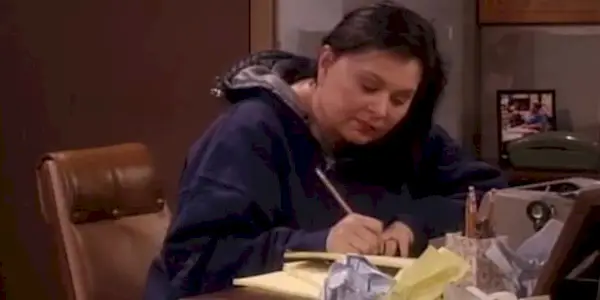 Roseanne Barr writing at her desk in the Roseanne series finale.