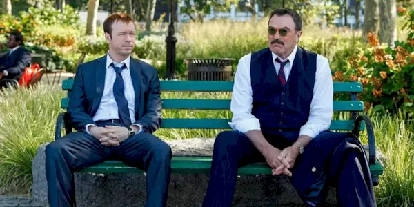 Donnie Wahlberg and Tom Selleck sit on a bench in Blue Bloods