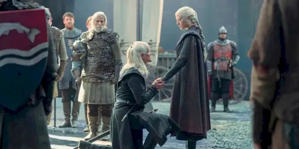Daemon Targaryen kneels in front of Rhaenyra Targaryen holding her hand in House of the Dragon Season 2.