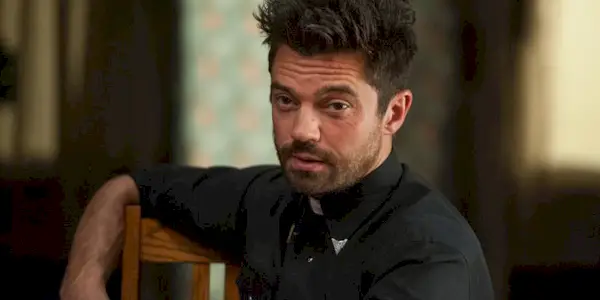 Dominic Cooper as Jesse Custer in his preacher attire sits talking to someone off camera.