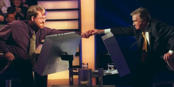 Regis reaching over to hold a male contestant