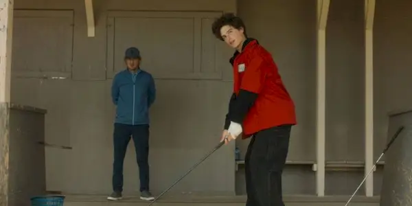 Owne Wilson as Pryce watching Peter Dager as Santi practice his swing in Stick.