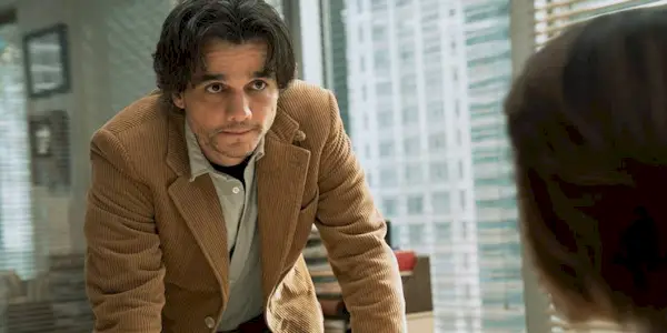 Wagner Moura as Dan Velasquez leaning on a desk in 