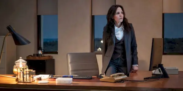 Mary-Louise Parker as Ms. Sigsby about to sit at her desk in The Institute