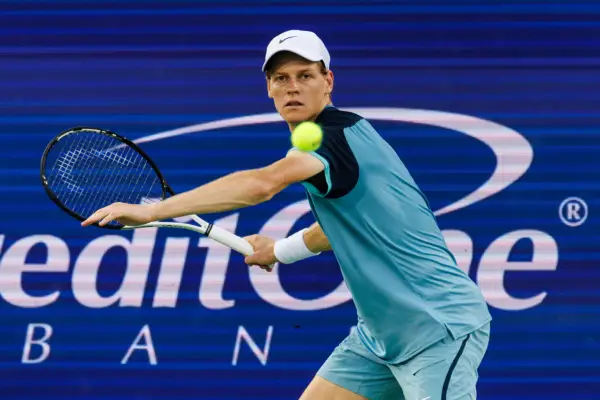 Jannik Sinner, in blue and black tennis kit and a white cap, prepares to hit a forehand at the Cincinnati Open 2024.