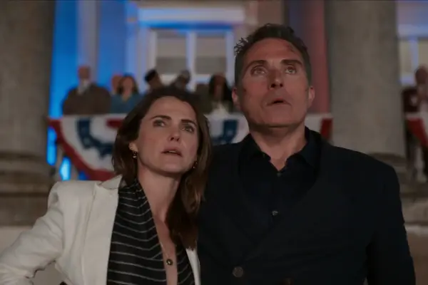Keri Russell and Rufus Sewell in The Diplomat. They are stood together looking shocked at something off screen