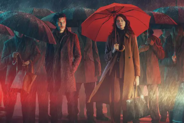 Colin Morgan and Emma Appleton on the key art of The Killing Kind; it shows their characters stood at a street crossing on a dark rainy night, with a crowd of people behind them and cars in front