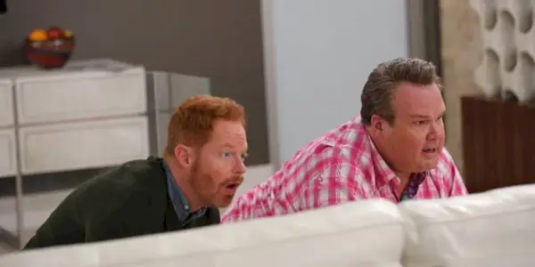 Jesse Tyler Ferguson and Eric Stonestreet hiding behind a sofa in 