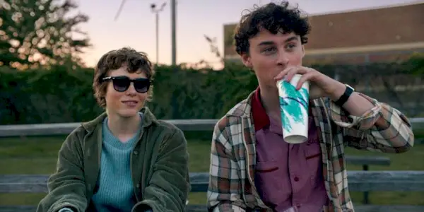 Sophia Lillis & Wyatt Oleff sit at a park bench and look in the same direction in I Am Not Okay With This.