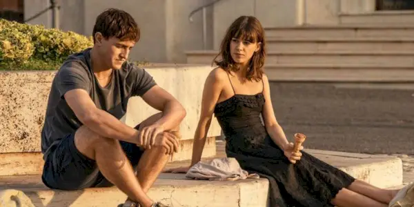 Two people sitting on the ground and talking to each other